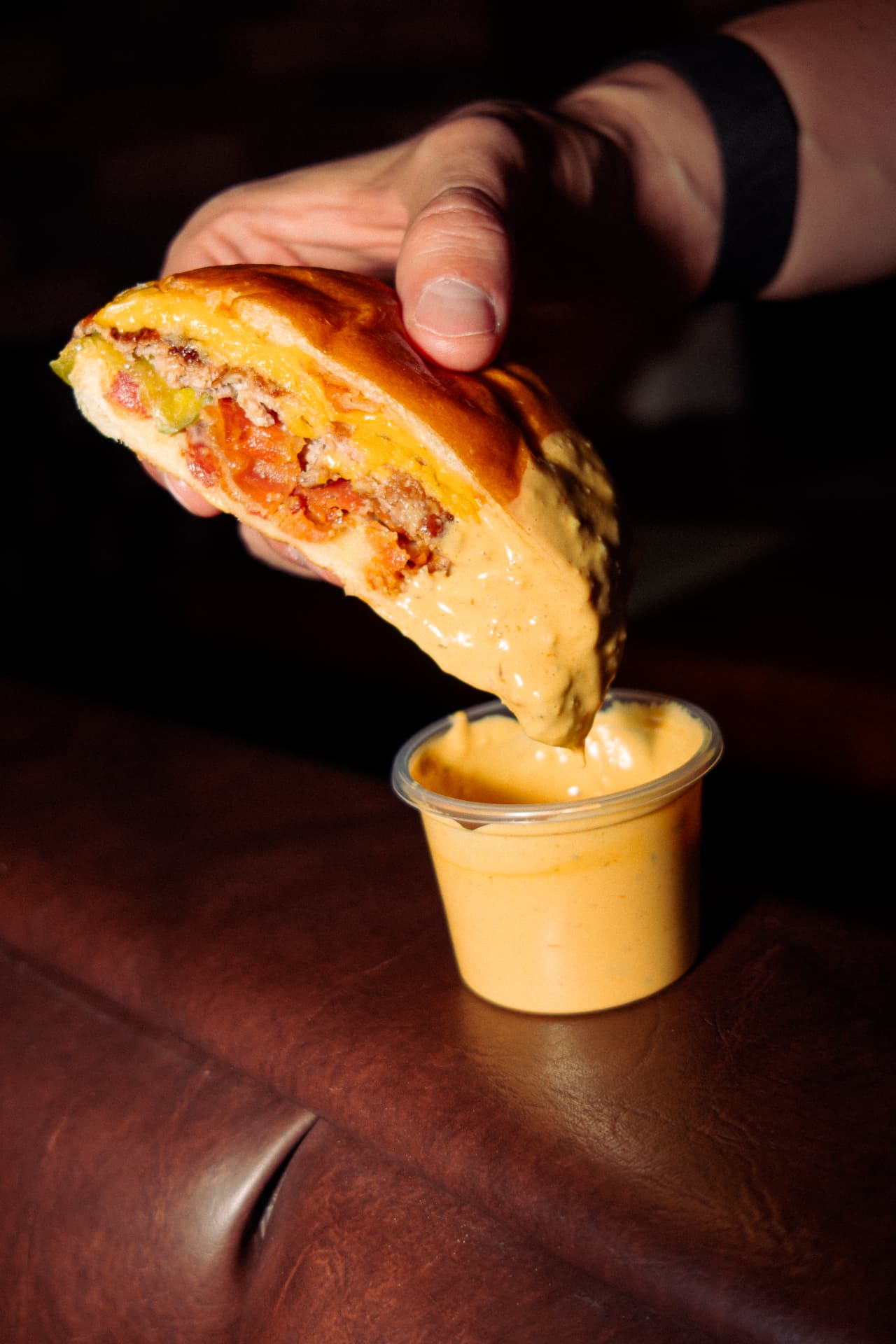Smash burger de Crust siendo remojada en Salsa Crust